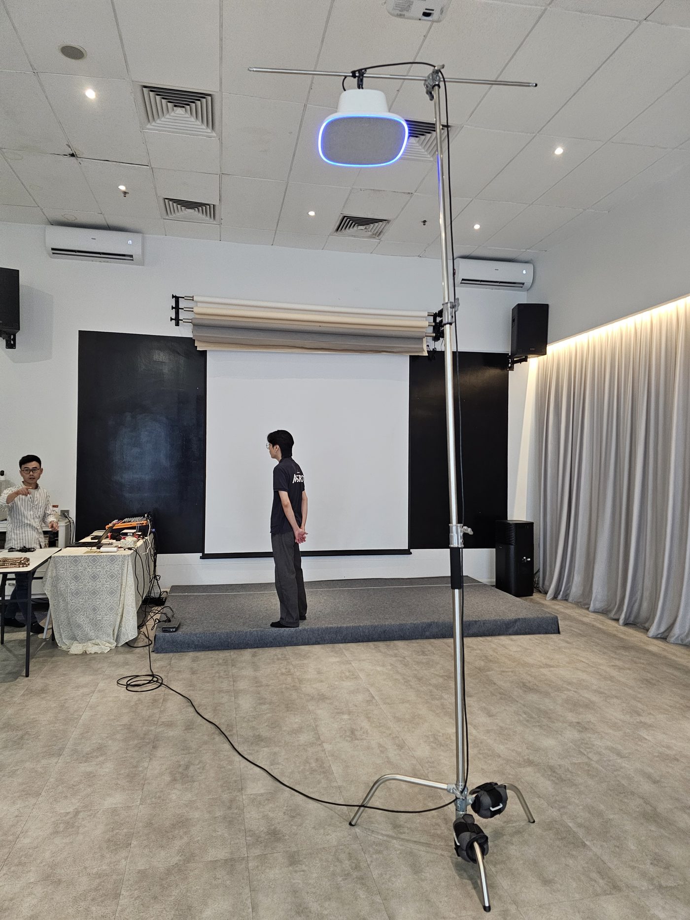 Event hall stage setup with projector screen, PA speakers and overhead lighting rig