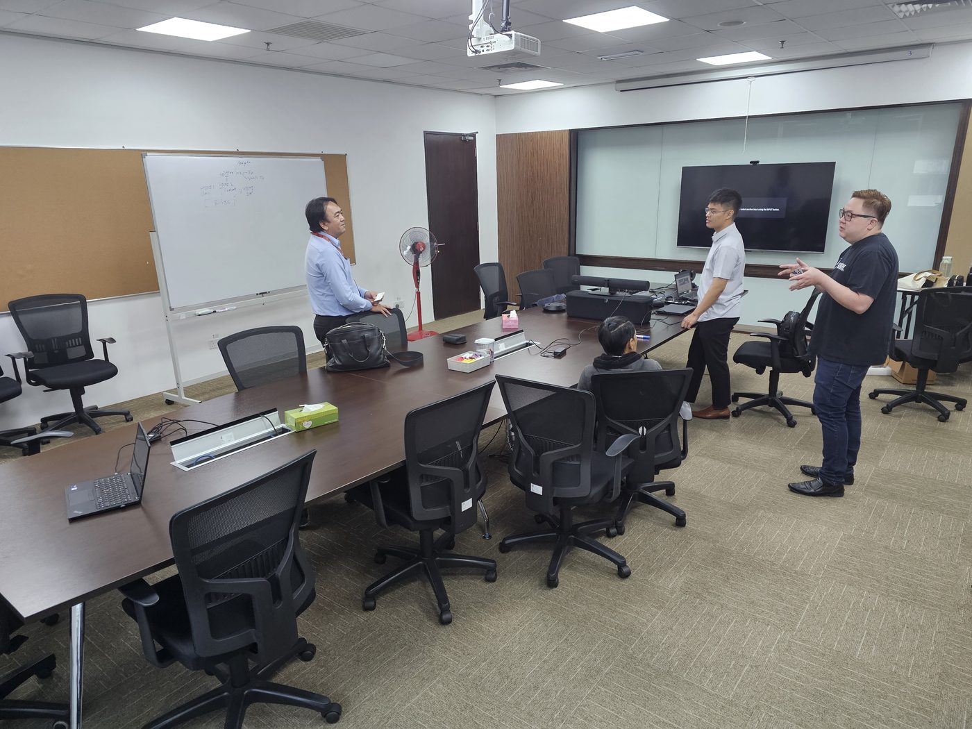 Training room briefing with team discussing AV display and conferencing setup