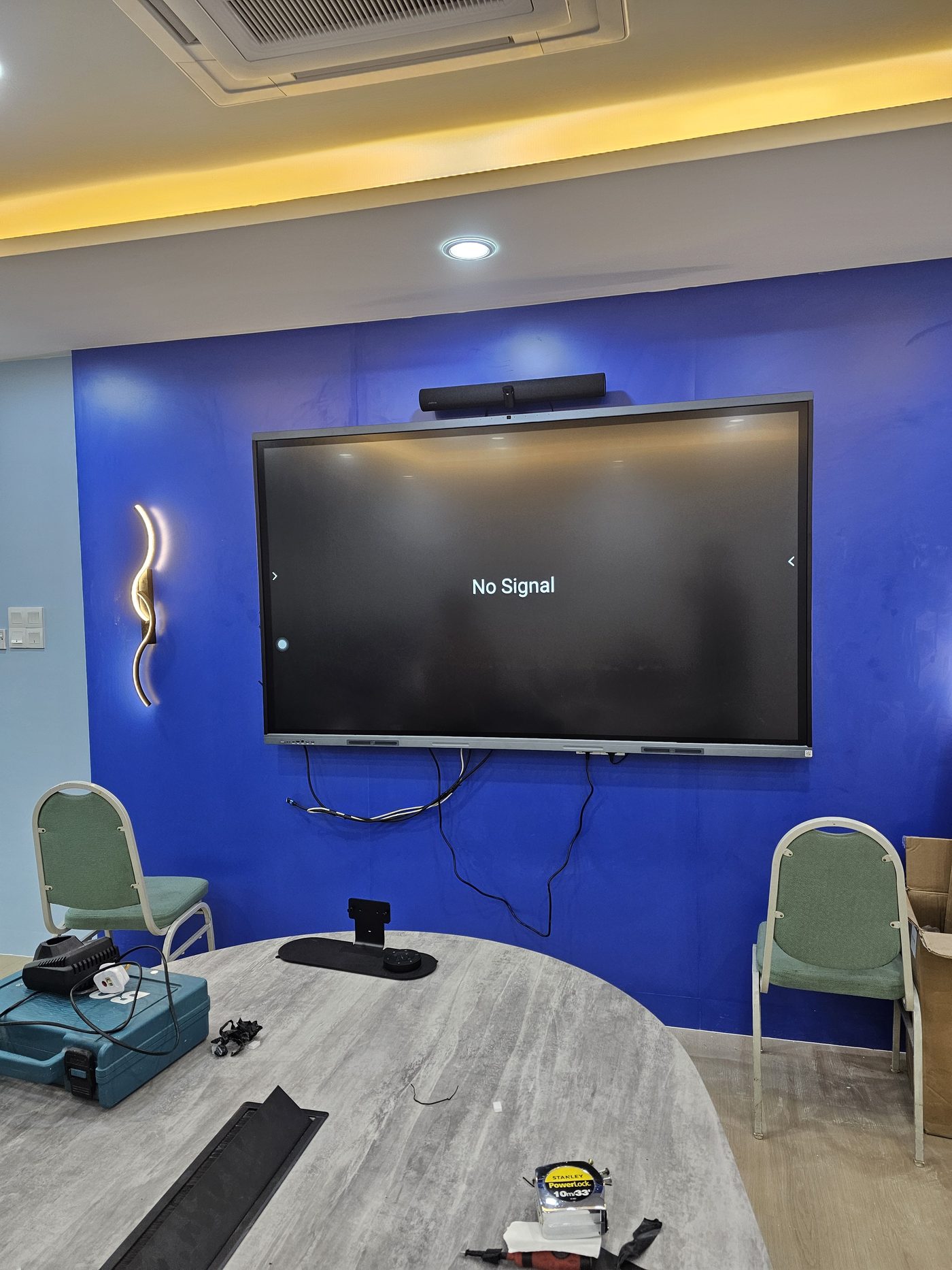 Huddle room display and Jabra soundbar mounted on accent wall, mid-installation