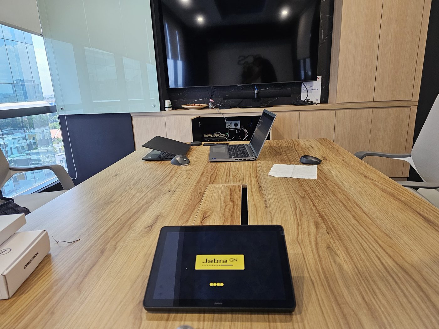 Boardroom display showing Crestron wireless presentation interface with touch controller and speakerphone puck
